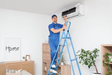 Fenerli erkek teknisyen odada klima kontrolü yapıyor.