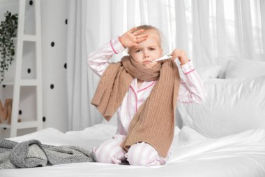 Yatak odasında termometresi olan hasta küçük kız.