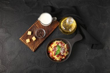 Lezzetli makarna ile kızartma tavası ve siyah arka planda malzemeler.