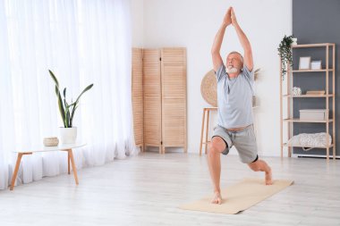 Sportif olgun adam evde yoga yapıyor.