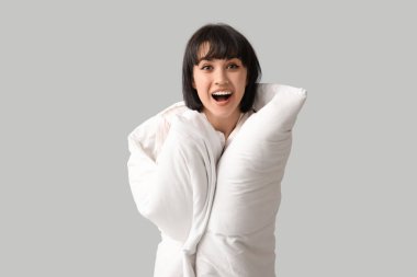 Gri arka planda battaniyesi olan güzel genç bir kadın.