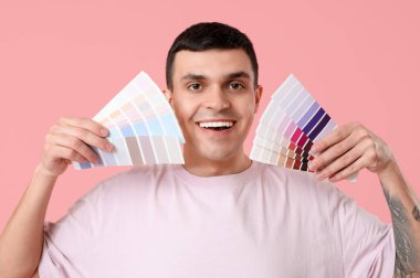 Pembe arka planda boya paletleri olan genç bir adam.