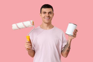 Pembe arka planda boya ve silindir kutusu olan genç bir adam.