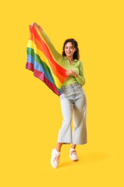 Sarı arka planda gökkuşağı bayrağı olan genç bir Afro-Amerikalı kadın. LGBT kavramı