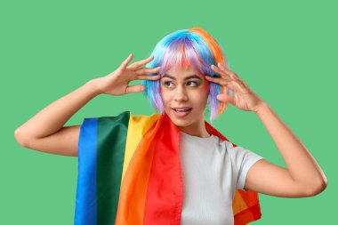 Yeşil arka planda gökkuşağı bayrağı olan genç bir Afro-Amerikalı kadın. LGBT kavramı