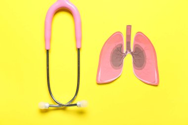 Paper lungs with stethoscope on yellow background
