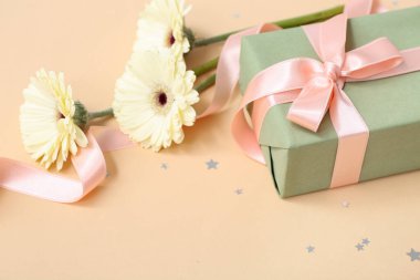 Güzel Gerbera çiçekleriyle hediye kutusu ve bej arka planda kurdele. Uluslararası Kadınlar Günü