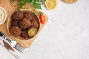 Nefis falafel köfteli ahşap kase, arka planda limon ve yeşillikler.