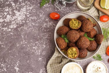 Nefis falafel köfteleri, soslar ve domateslerle dolu bir kase.