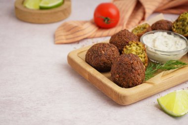 Nefis falafel köfteli ahşap tahta tahta, arka planda sos ve limon, yakın plan.