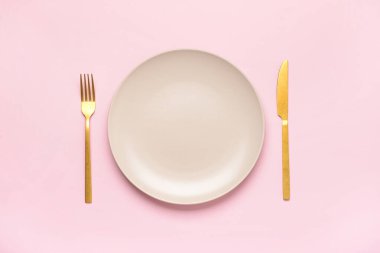 Pembe arka planda temiz tabak ve çatal bıçak takımı