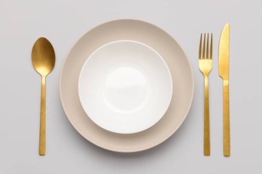 Beyaz arkaplanda altın çatal bıçak takımı olan bulaşık takımı