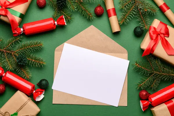 Zarflı boş kağıt, Noel süsü ve yeşil arka planda hediyeler. Noel Baba 'ya mektup