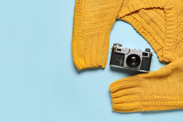 Renkli arka planda sıcak süveter ve fotoğraf makinesi