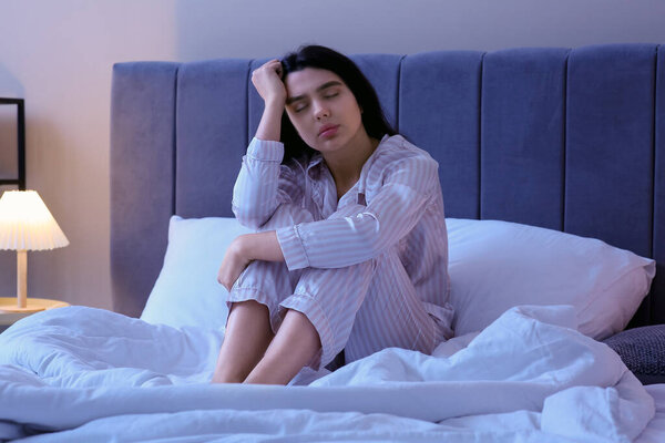 Beautiful young woman suffering from insomnia in bedroom at night