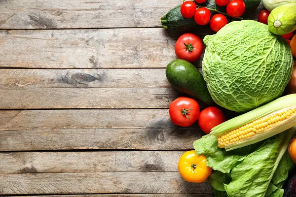 Gri ahşap arka planda farklı taze sebzeler.