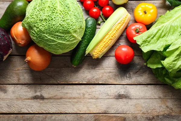 Gri ahşap arka planda farklı taze sebzeler.