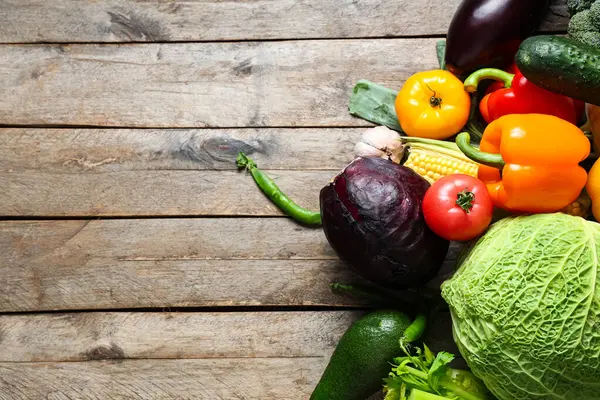 Gri ahşap arka planda farklı taze sebzeler.