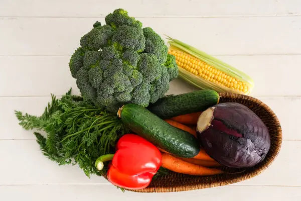 Hasır kase beyaz ahşap arka planda farklı taze sebzelerle