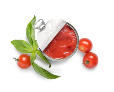 Beyaz arka planda domates ve fesleğenle açılmış teneke kutu.