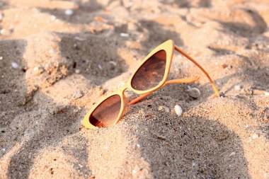 Kumlu arka planda şık bej güneş gözlükleri