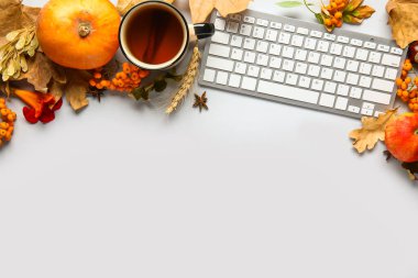 Sonbahar yapraklı klavye ve beyaz arka planda bir fincan çay
