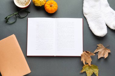 Açık kitaplı kompozisyon, ılık çoraplar ve koyu arkaplanda sonbahar dekoru