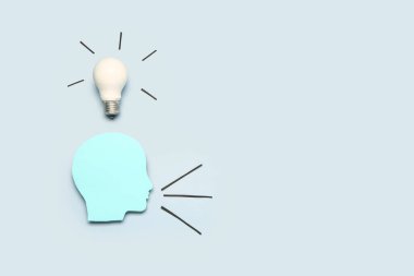 Gri arka planda ampullü kağıt insan kafası. İş fikri kavramı