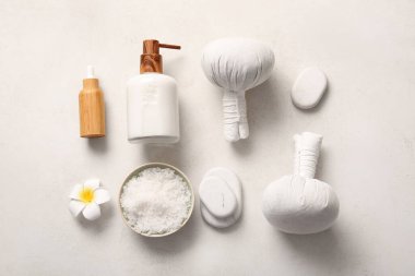 Beyaz arka planda bitkisel poşetler, taşlar ve kozmetik ürünler içeren güzel bir spa kompozisyonu
