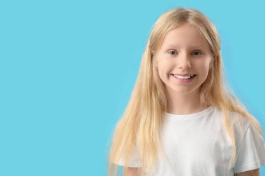 Mavi arka planda sağlıklı dişleri olan mutlu küçük kız.