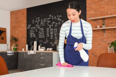 Kahve dükkanındaki Asyalı kadın barista masasını temizliyor.