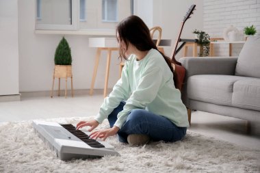 Evde sentezleyici çalan genç bir kadın.