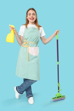 Mavi arka planda paspası ve bir şişe deterjanı olan güzel bir kadın.