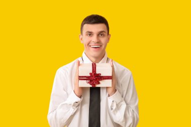 Sarı arka planda hediye kutusu olan yakışıklı bir adam.