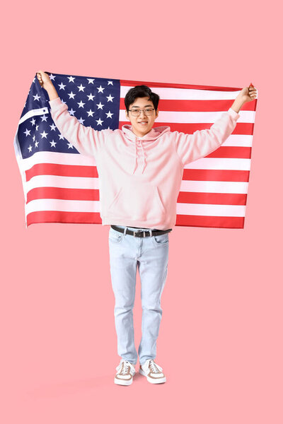 Young Asian man with USA flag on pink background