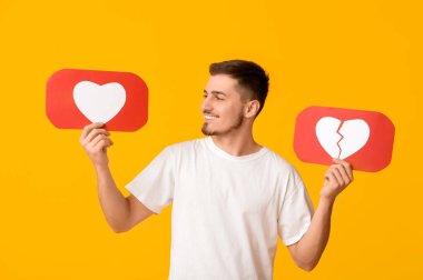 Sarı arka planda ikonları seven ve sevmeyen yakışıklı, mutlu genç bir adam.