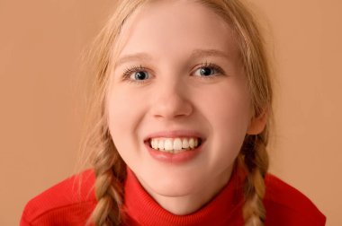 Bej arka planda gülümseyen genç kız, yakın plan.