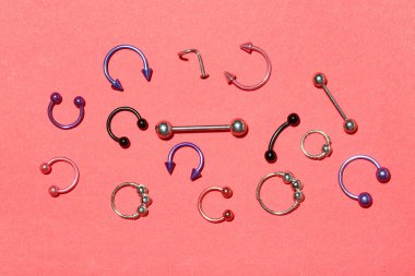 Kırmızı arka planda piercing için şık mücevherleri olan kompozisyon