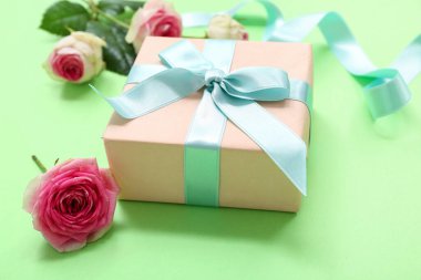 Yeşil arka planda güzel gülleri ve kurdelesi olan hediye kutusu. Uluslararası Kadınlar Günü