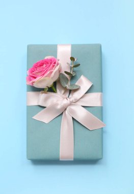 Mavi arka planda güzel bir gül ve okaliptüs olan hediye kutusu. Uluslararası Kadınlar Günü