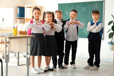 Sınıfta kalp hareketi yapan sevimli küçük öğrenciler. Okul tatili kavramı