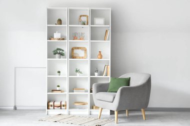 Oturma odasında yapay bitki ve koltuk bulunan raf ünitesi.