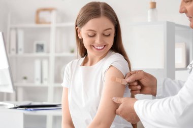 Klinikte aşıdan sonra tıbbi yama uygulayan genç bir kadın.