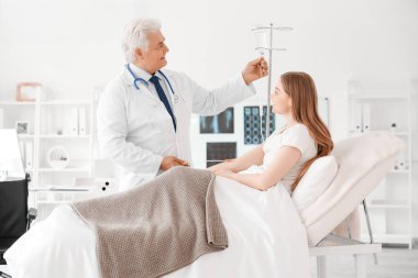 Klinikte serumu olan olgun doktor ve kadın hasta.