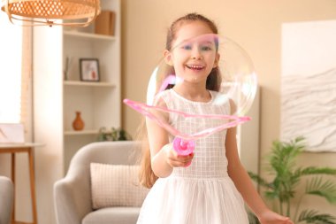 Şirin küçük kız evde sabun köpüğü yapıyor.