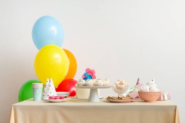 Beyaz duvara karşı doğum günü partisi için farklı şekerlemeler ve balonlar.