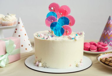 Beyaz duvara karşı doğum günü partisi için pasta, şeker ve hediye kutusu.