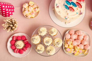 Tatlı standı, lezzetli beyaz kekler ve pembe masadaki doğum günü partisi için diğer tatlılar.