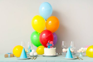 Beyaz duvara karşı pasta, şeker ve doğum günü partisi için dekorasyon masası.