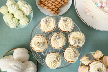 Turkuaz masada doğum günü partisi için lezzetli beyaz kekler ve diğer tatlılar ile tatlı standı.